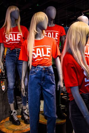 decoration of the entrance to the store in the mall. signboard sale with white letters on a red background.discounts at the mall, Mannequins in a window of a clothing store in T-Shirts With Signs Advertising Saleの写真素材