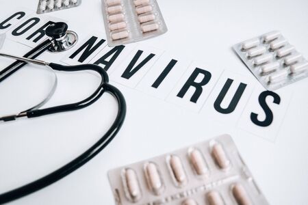 The word Coronavirus on a white background with Medical stethoscope or phonendoscope with syringe