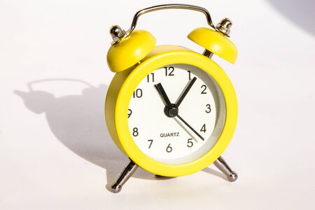 Yellow alarm clock on white background, copy space, Cute yellow metal alarm clock with large shadow...
