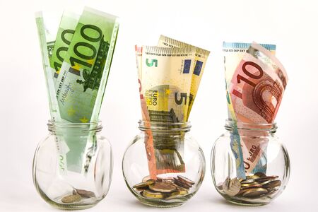 Glass jars filled with coins and Euro bills, savings, money, ank money, crisis, cash, banknotes, coins, saving, economy, finance, savings, income, financial growth, earnings account bank money capital investment glass jar businessの写真素材