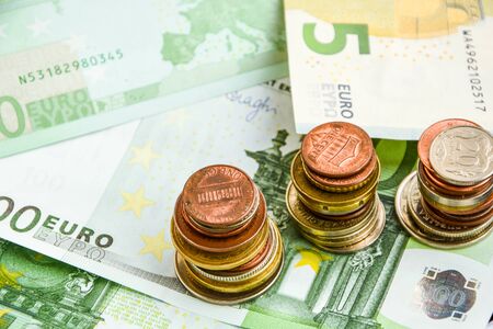 Euro coins on banknote money background, a coin on the background of stacks of coins and banknotes