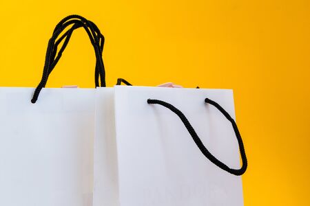 Set of white paper bags for shopping on yellow background. Mockup for design, copy space, shopping...