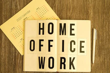 lightbox with text HOME OFFICE WORK with notebook pen and headphones, copy space wooden table background, quarantine and isolation HOME OFFICE, coronavirus, europeの写真素材