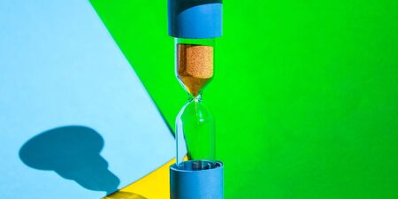 Hourglass colored background, copy space for text, Hourglass shows that time is running out, sand glass, The concept of time, delay, morning rise, the appointed meetingの写真素材