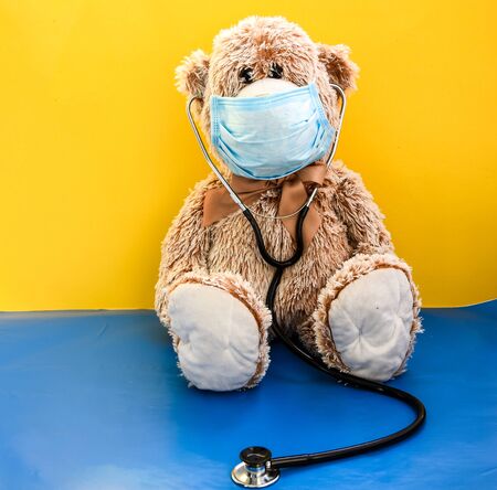 Coronavirus covid-19 and pollution protection concept. teddy bear doll wearing mask and phonendoscope, stethoscope on yellow background, copy space, Medical care, Quarantine 2020の写真素材