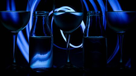 luxury splash drink in a glass on a high leg on a colored background with dark light behind, a bar rack in restaurant.の写真素材