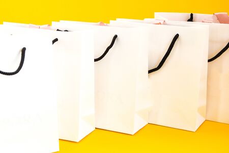 Set of white paper bags for shopping on yellow background. Mockup for design, copy space, shopping bag and copy space for plain text or productの写真素材
