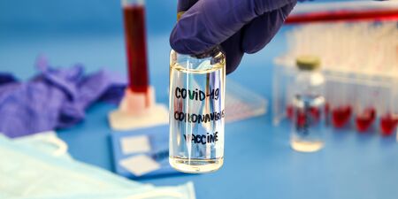 Doctor or nurse hand with nitrile glove holding coronavirus vaccine shot for vaccination, medicine...
