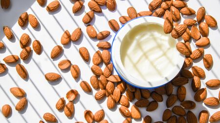 jar with facial or body almond moisturizer jar open with almonds on the table. Top view. Horizontal...