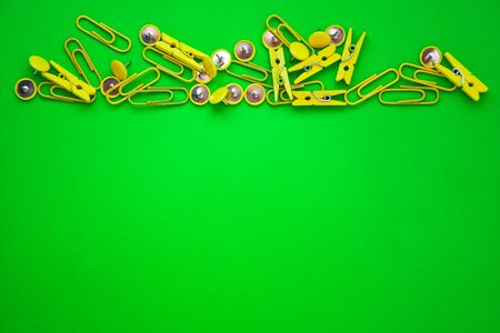 Office supplies in the form of colored buttons and paper clips, clothepins on yellow and green background, copy space, border and frame, back to school concept of office chanceryの写真素材