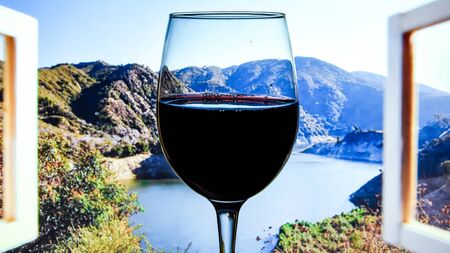 Closeup of glass of red wine in Italy Tuscany on windowsill window with view of mountains, copy space, vacation time, relaxingの写真素材