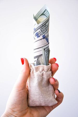 Businessman hand with a bag full of dollar banknotes on white, copy space for text, hand holding curencies dollars, 100 bill of us curencyの写真素材