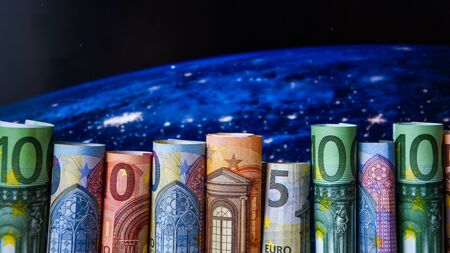 globe map and many euro bills rolled up, copy space for text, banknotes euros the map background, close-upの写真素材