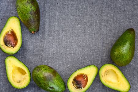 Opened avocado showing seed on textured grey linel background. Top view, Copy space, organic healthy...
