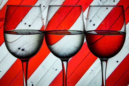 three alcoholic glass in the club entourage, copy space, red background, white, red or rose wine, alcohol drinksの写真素材