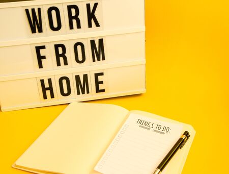lightbox with text WORK FROM HOME with notebook pen and TO DO list, copy space on yellow background, quarantine and isolation HOME OFFICE, coronavirus, europeの写真素材
