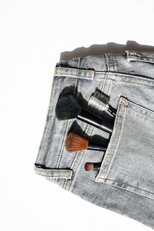 Large makeup brushes in pocket of gray jeans. Concept, commercial work of a makeup artist, for...