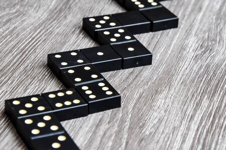 black Domino dice on a light wooden table, the process of playing dominoes, selective focus, close up, table gameの写真素材