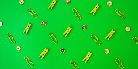 Office supplies in the form of colored buttons and paper clips, clothepins on yellow and green background, copy space, border and frame, back to school concept of office chanceryの写真素材