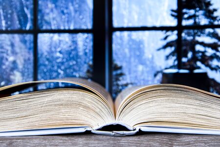 Closeup of a hardcover book open in the middle, Open book, copy space for text, winter window backgroundの写真素材