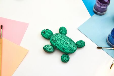Painting a rock green turtle on a stone step by step. Children art project. DIY concept. Step by step photo instruction.View from above. Work with children and adults in quarantine.の写真素材