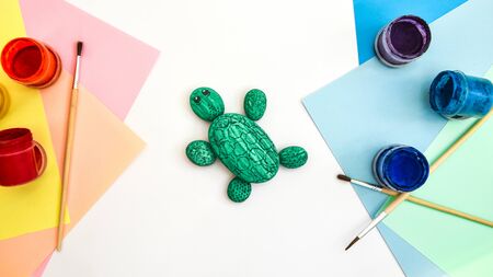 Painting a rock green turtle on a stone step by step. Children art project. DIY concept. Step by step photo instruction.View from above. Work with children and adults in quarantine.の写真素材