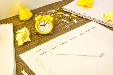 Weekly planner with alarm clock and office supplies. Business planning, workplace. paper