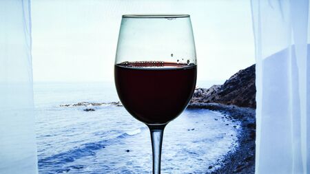 Glass of red wine served outdoor on tropical island, Canary islands, Spain with beautiful blue ocean view from the window, vacation time, copy space for textの写真素材