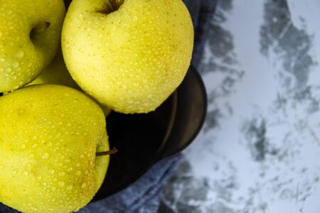 Close up of green Granny Smith and golden apples in the kitchen towel and bowl, water drops wet apples, fresh healthy nutritionの写真素材