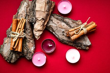 Spa still life treatment with candles, cinnamon sticks bark on red background, copy space for textの写真素材
