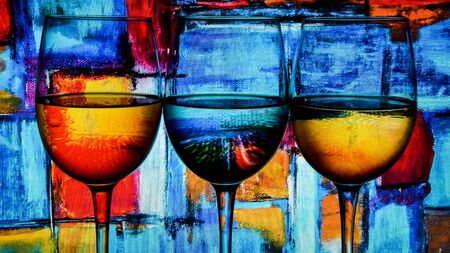 Three wine glasses in a row with colorful light painting behind, Set of three wine glasses with red, white and rose wine, banner, alcohol drinksの写真素材