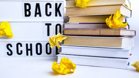 lightbox with BACK TO SCHOOL text and books on white background, Stack of old book education concept background, many books piles with copy space for text crumpled yellow paperの写真素材
