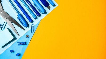 Overhead shot of school supplies, Blue stationary on yellow background, copy space for text, scissors, pencil, pen clothespin and paper clips, back to schoolの写真素材