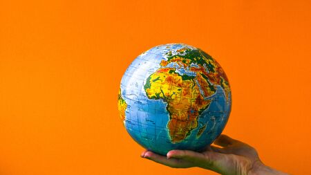 The globe in children's hands on colorful background. Copy space for text. World globe on a palm. Globalization Concept. Environmental conversationの写真素材