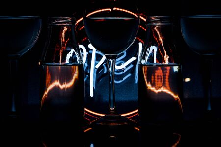 luxury splash drink in a glass on a high leg on a colored background with dark light behind, a bar rack in restaurant.の写真素材