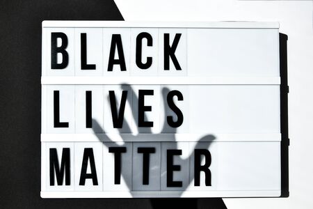 BLACK LIVES MATTER text with deep shadows of hand on a black and white background. Protest against the end of racism, anti-racism, equality. Poster on violation of human rightsの写真素材