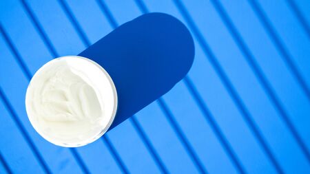 white cream in a bowl on blue background with deep shadow, Jar of cream with a shadow, Face cosmetics, Beauty blogger, procedures salon conceptの写真素材