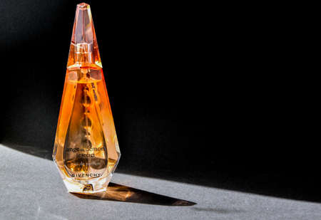Zhytomyr, Ukraine - June 2, 2020. A clear orange glass spray bottle of Givenchy Ange ou Demon Le secret Parfum for woman on color background, Female perfumeのeditorial素材