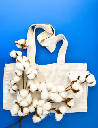 Stylish eco bags and cotton flowers on blue background, Zero waste concept. Eco-friendly shopping. Fluffy cotton flowers and Organic bags, top viewの写真素材