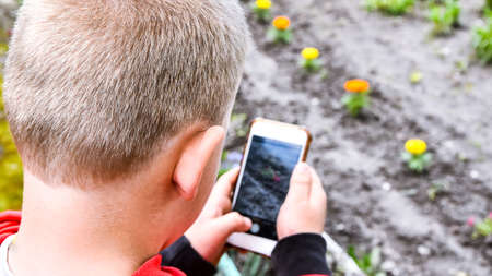 Small boy with smartphone in his hands is mastering new technologies, taking photos, small...