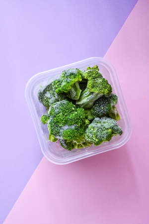 Broccoli in a plastic container for long-term storage. Deep freezing of vegetables. Frozen food vegetables on color background. Copy space for text. Stocking up vegetables for winter storageの写真素材