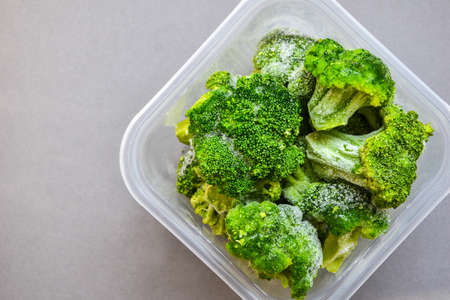 Broccoli in a plastic container for long-term storage. Deep freezing of vegetables. Frozen food vegetables on gray background. Copy space for text.の写真素材