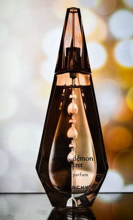 Zhytomyr, Ukraine - June 2, 2020. A clear orange glass spray bottle of Givenchy Ange ou Demon Le secret Parfum for woman on color background, Female perfumeのeditorial素材