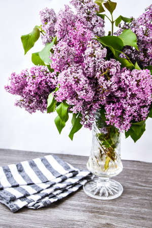 Lilac spring bouquet in glass vase on table with scissors and rope, copy space, holiday congratulation backgroundの写真素材