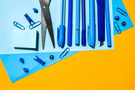 Overhead shot of school supplies, Blue stationary on yellow background, copy space for text, scissors, pencil, pen clothespin and paper clips, back to schoolの写真素材