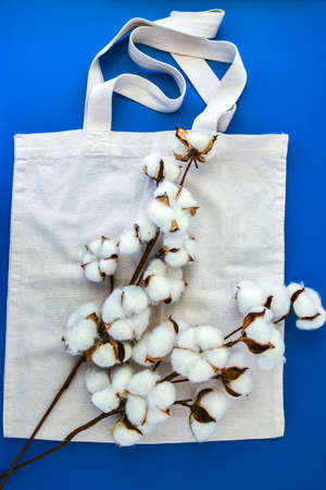 Stylish eco bags and cotton flowers on blue background, Zero waste concept. Eco-friendly shopping. Fluffy cotton flowers and Organic bags, top viewの写真素材