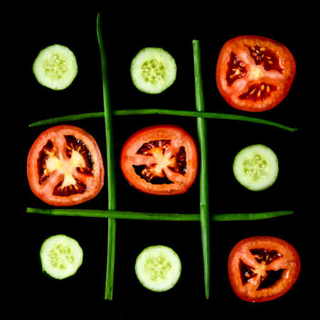 Diet concept hazardous game for health tic tac toe made of tomatoes cucumbers and green onion, vegan vegetarian foodの写真素材