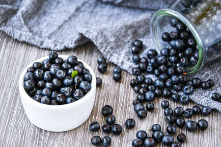 Small White Bowl of Organic Blueberries on Wooden Table with kitchen towel. Copy space. Summer fruit berries. Fresh forest berryの写真素材