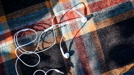 Headphones on the cozy sweaters. Top view. Autumn flatlay. Outdoor listening podcasts. Sunlightの写真素材