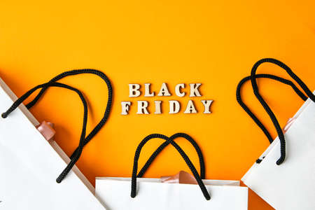 Wooden letters text BLACK FRIDAY with packaging bags in front yellow background, copy space, banner Top view Flat lay seasonal sale, retail, shopping concept. Black friday saleの写真素材